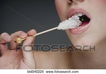 Stock Photography - Woman eating rock candy. Fotosearch