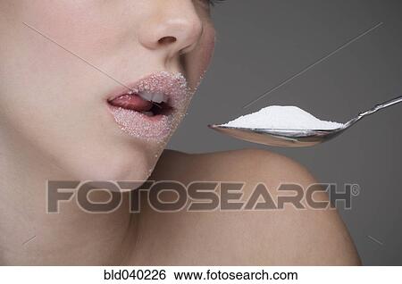 Stock Photograph - Woman eating spoon of sugar. Fotosearch