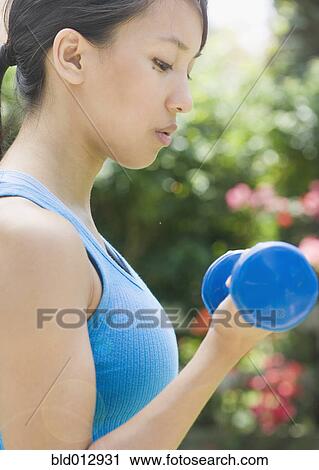Woman exercising with dumbbell View Large Photo Image Stock Image - Woman exercising with dumbbell. Fotosearch