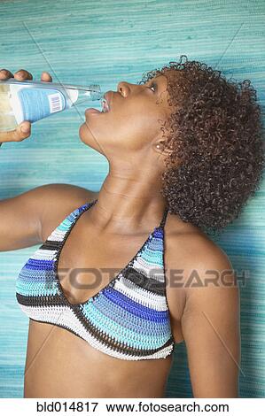 Stock Photo - Woman in bikini drinking bottled water. Fotosearch