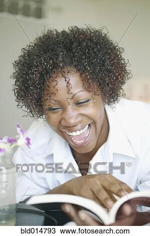 Stock Image - Woman laughing and reading book. Fotosearch