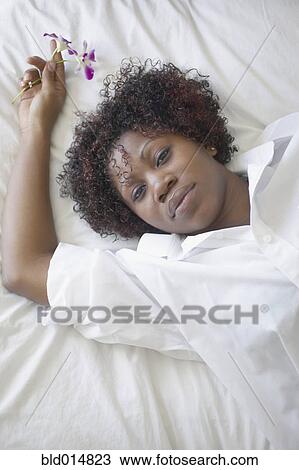 Woman laying on bed holding flowers View Large Photo Image Stock Image - Woman laying on bed holding flowers. Fotosearch