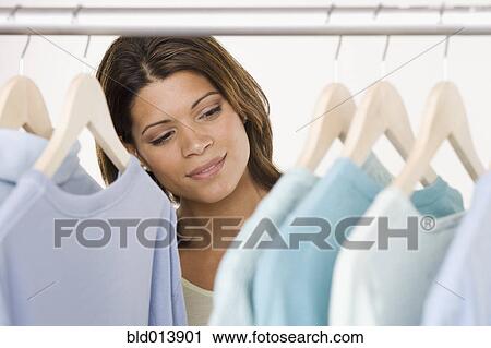 Woman looking at shirts in closet View Large Photo Image Stock Image - Woman looking at shirts in closet. Fotosearch