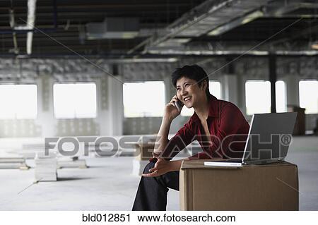Stock Image - Woman on mobile phone at construction site. Fotosearch
