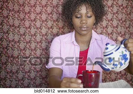 Stock Image - Woman pouring cup of tea. Fotosearch