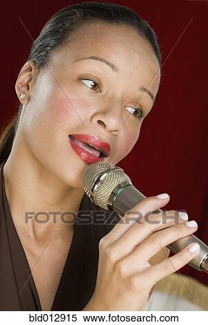 Woman singing into microphone View Large Photo Image Stock Photography - Woman singing into microphone. Fotosearch