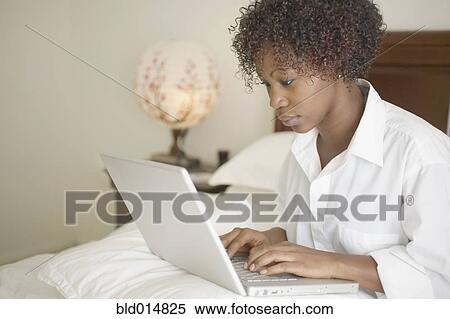 Woman sitting in bed with laptop View Large Photo Image Stock Photography - Woman sitting in bed with laptop. Fotosearch
