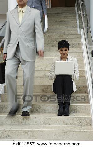 Woman sitting on steps with laptop View Large Photo Image Stock Photo - Woman sitting on steps with laptop. Fotosearch