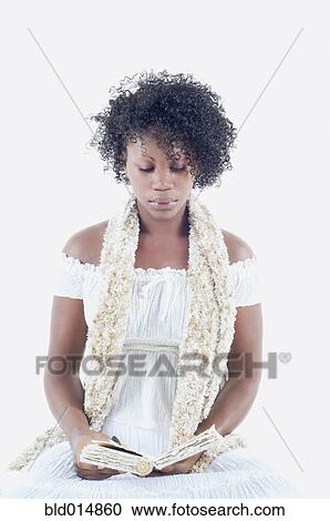Stock Image - Woman wearing dress and scarf reading book. Fotosearch