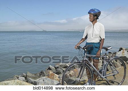 Stock Photo - Woman with bike looking out over lake. Fotosearch