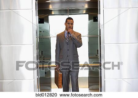 Stock Image - Young businessman inside elevator. Fotosearch