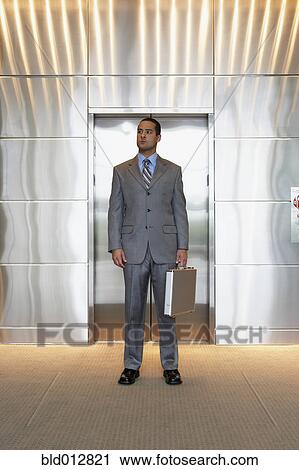 Young businessman standing outside of elevator View Large Photo Image Stock Image - Young businessman standing outside of elevator. Fotosearch