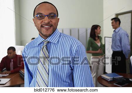 Young businessman with coworkers in background View Large Photo Image Stock Photograph - Young businessman with coworkers in background. Fotosearch