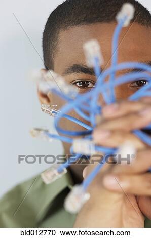 Stock Image - Young man holding Ethernet cables. Fotosearch