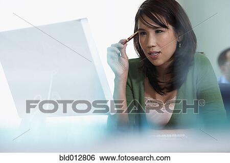 Stock Photograph - Young woman looking at computer monitor. Fotosearch