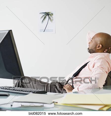 Stock Photography - African American businessman looking at picture of palm tree. Fotosearch