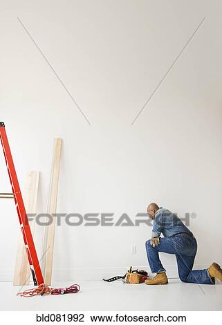 African American construction worker kneeling to look at wall View Large Photo Image Stock Image - African American construction worker kneeling to look at wall. Fotosearch