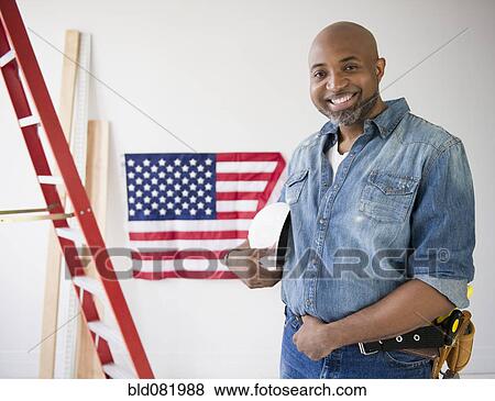 African American construction worker holding hard-hat near American flag View Large Photo Image Stock Photo - African American construction worker holding hard-hat near American flag. Fotosearch