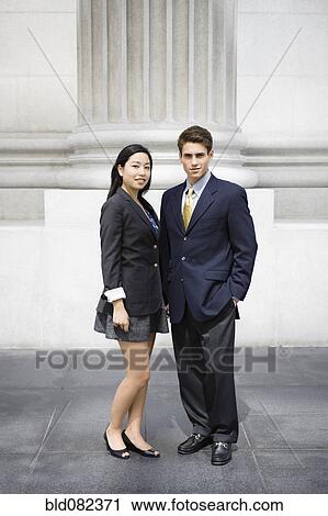Stock Image - Business people standing near stone column. Fotosearch