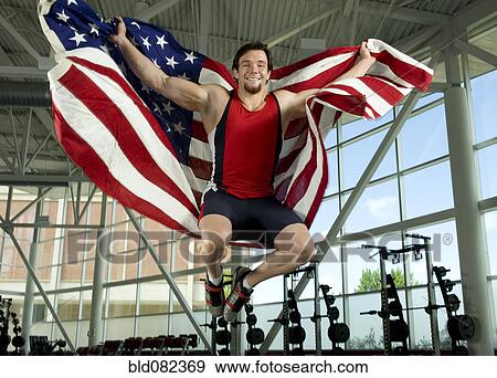 Stock Photo - Caucasian athlete jumping with American flag. Fotosearch
