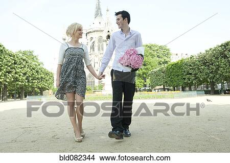 Caucasian couple holding hands in park near Notre Dame View Large Photo Image Picture - Caucasian couple holding hands in park near Notre Dame. Fotosearch
