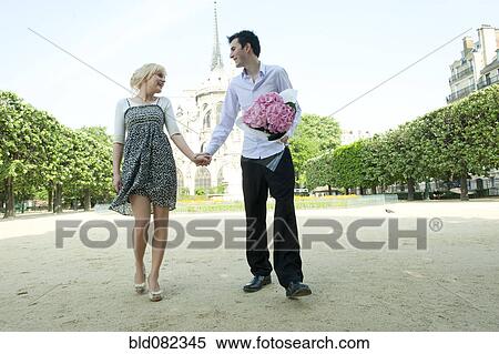 Stock Photography - Caucasian couple holding hands in park near Notre Dame. Fotosearch