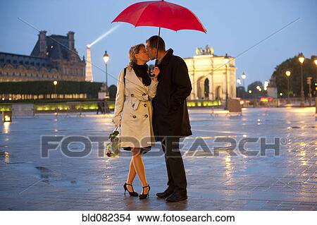 Caucasian couple kissing in rain at night near the Louvre View Large Photo Image Picture - Caucasian couple kissing in rain at night near the Louvre. Fotosearch