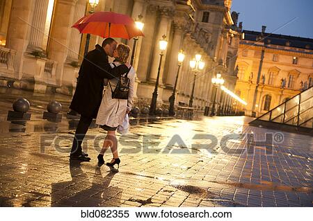 Caucasian couple kissing in rain at night at the Louvre View Large Photo Image Stock Photography - Caucasian couple kissing in rain at night at the Louvre. Fotosearch