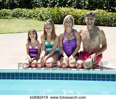 Stock Photo - Caucasian family sitting near swimming pool. Fotosearch
