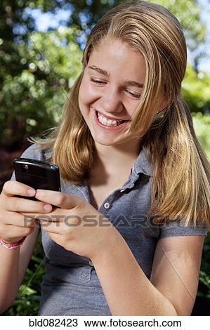 Stock Image - Caucasian girl text messaging on cell phone. Fotosearch