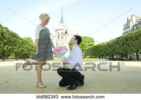 Caucasian man proposing to girlfriend in park near Notre Dame View Large Photo Image Stock Image - Caucasian man proposing to girlfriend in park near Notre Dame. Fotosearch