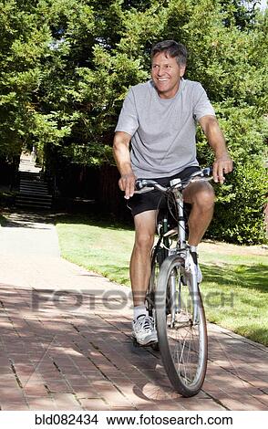 Picture - Caucasian man riding bicycle. Fotosearch