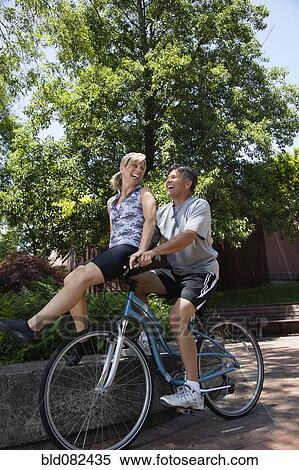 Caucasian man riding wife on handlebars View Large Photo Image Stock Photography - Caucasian man riding wife on handlebars. Fotosearch
