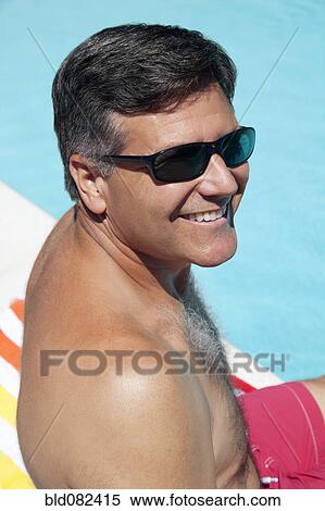 Stock Photography - Caucasian man sitting near swimming pool. Fotosearch