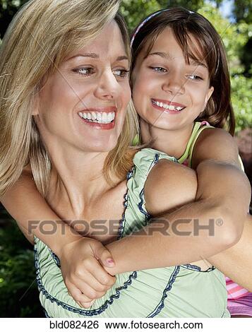 Stock Photograph - Caucasian mother giving daughter piggyback ride. Fotosearch