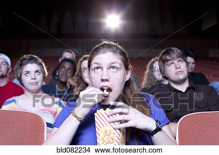 Caucasian woman eating popcorn in movie theater View Large Photo Image Picture - Caucasian woman eating popcorn in movie theater. Fotosearch