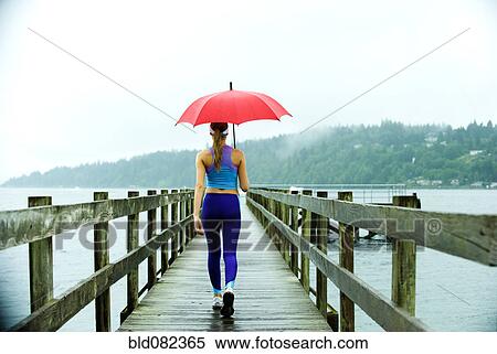 Caucasian woman in sportswear with red umbrella on pier View Large Photo Image Stock Photography - Caucasian woman in sportswear with red umbrella on pier. Fotosearch