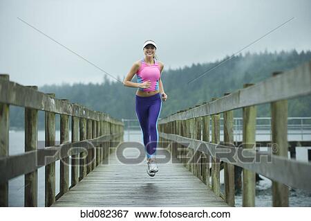 Caucasian woman running on pier View Large Photo Image Stock Photo - Caucasian woman running on pier. Fotosearch