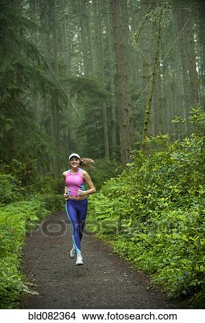 Picture - Caucasian woman running on remote path. Fotosearch