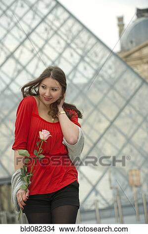 Picture - Caucasian woman standing at the Louvre with rose. Fotosearch