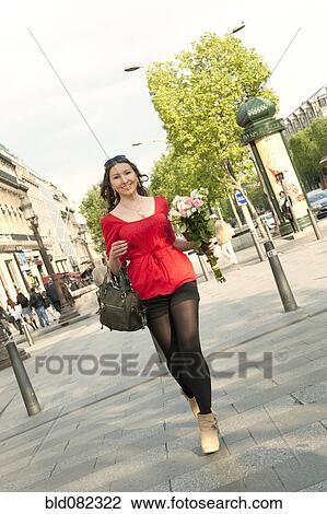 Stock Image - Caucasian woman walking and holding bouquet. Fotosearch