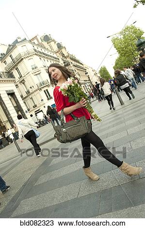 Stock Image - Caucasian woman walking and holding bouquet. Fotosearch