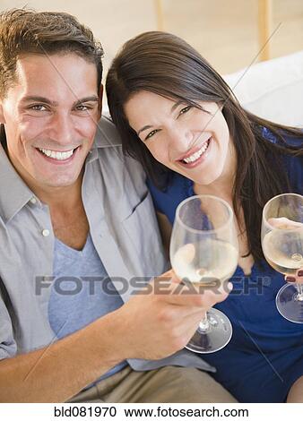 Stock Image - Couple drinking white wine and toasting. Fotosearch