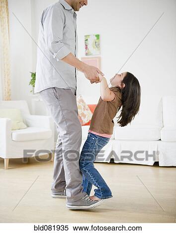 Stock Photography - Daughter standing on father's feet and dancing. Fotosearch