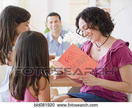 Stock Image - Daughters giving mother Mother's Day card. Fotosearch