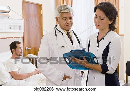 Doctor and nurse discussing patient in hospital room View Large Photo Image Stock Photograph - Doctor and nurse discussing patient in hospital room. Fotosearch