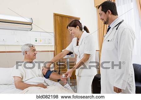Doctor and nurse examining patient in hospital room View Large Photo Image Stock Photo - Doctor and nurse examining patient in hospital room. Fotosearch