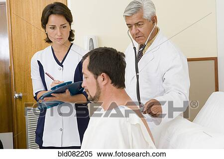Stock Photography - Doctor and nurse examining patient in hospital room. Fotosearch