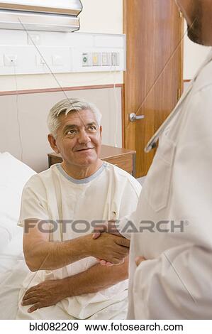 Stock Photo - Doctor shaking patient's hand in hospital room. Fotosearch