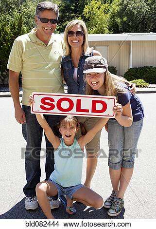 Excited Caucasian family holding "sold" sign View Large Photo Image Picture - Excited Caucasian family holding "sold" sign. Fotosearch